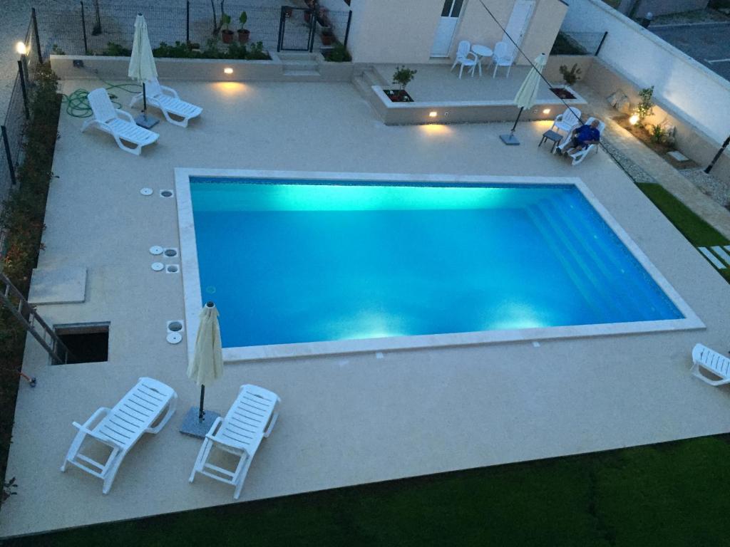 an overhead view of a swimming pool with chairs and umbrellas at Guest House Punta Grzan in Petrcane