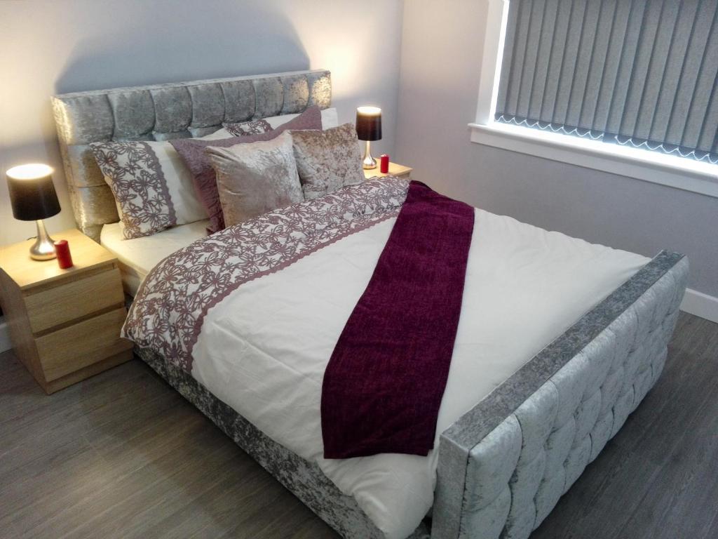 a bedroom with a large bed with a purple tie on it at Central Ayr Main Road Apartment in Ayr