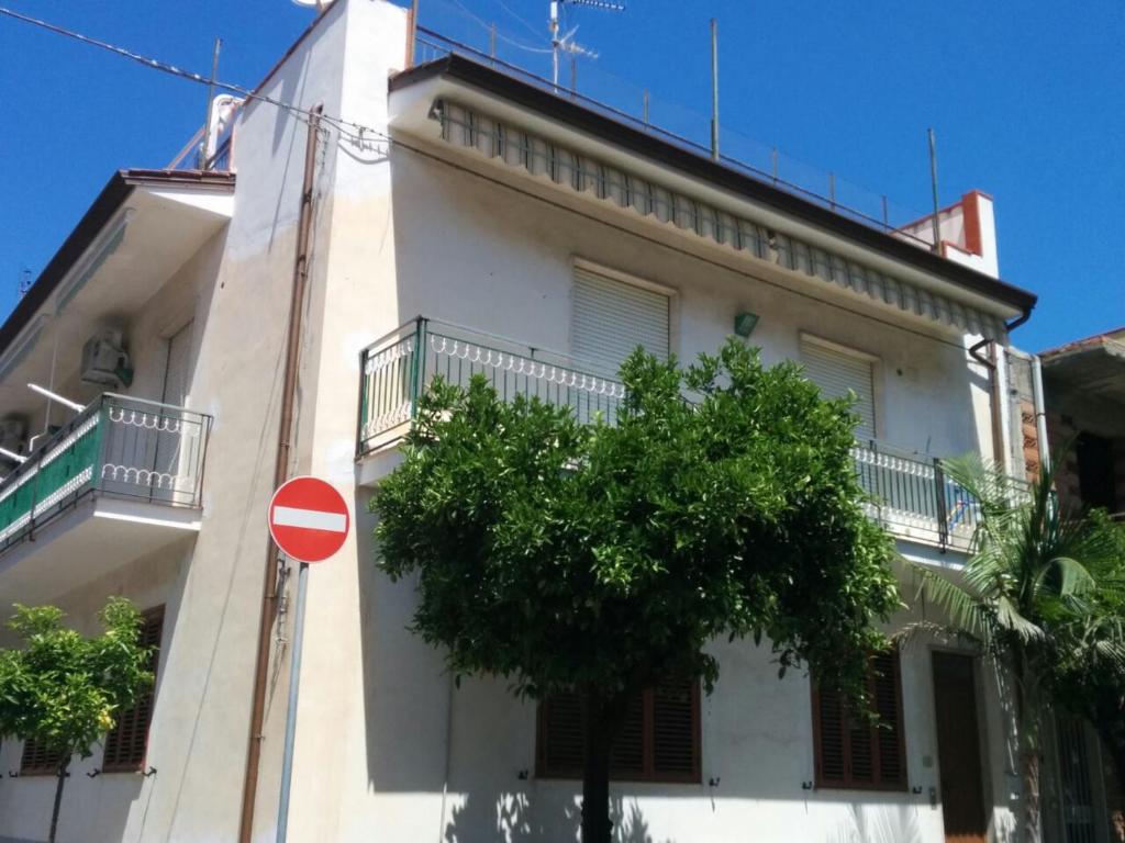 un edificio blanco con un árbol delante en Ventura CasaVacanze, en Oliveri