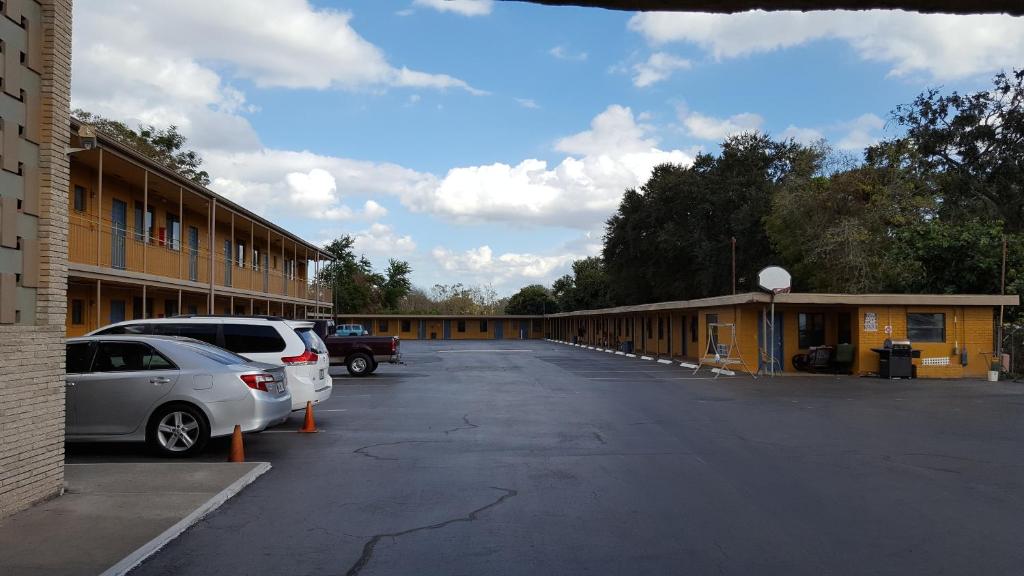 un parking avec des voitures garées devant un bâtiment dans l'établissement Budget Motel, à Orlando