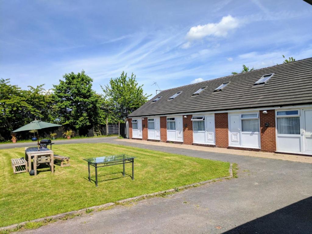 a building with a table and an umbrella in the yard at Chelford Guesthouse in Marthall