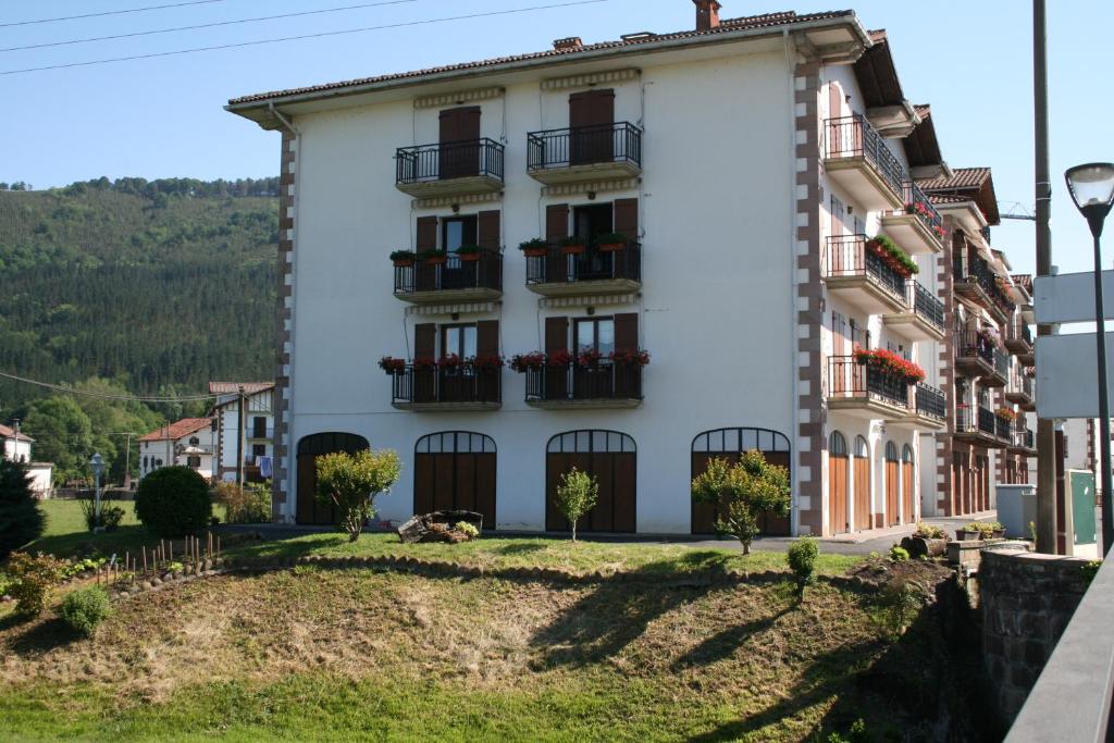 a white building with balconies on a street at Apartamento Rural Elizondo in Elizondo