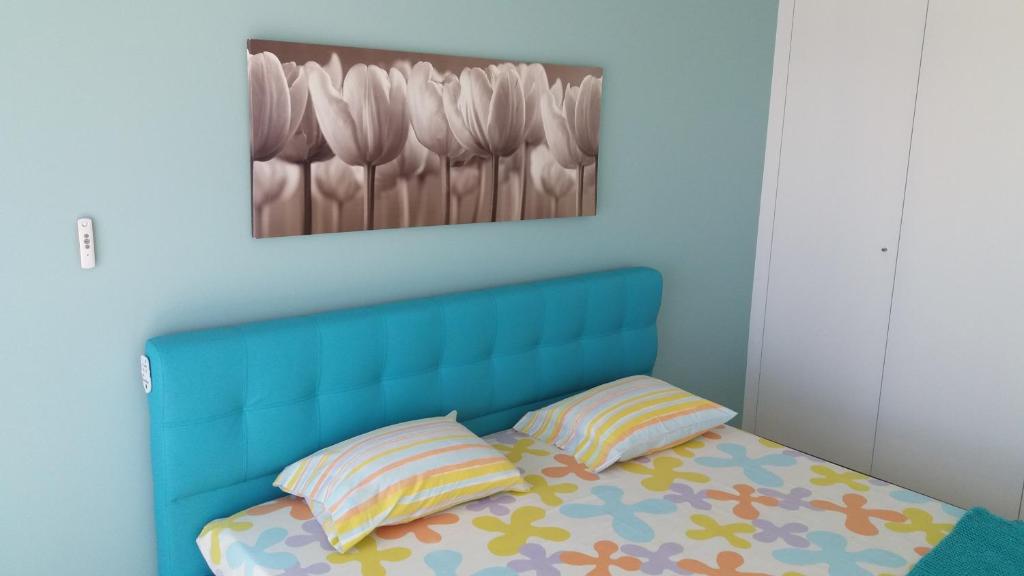 a bed with a blue head board and two pillows at Blue Anchor Apartment in Vila Praia de Âncora