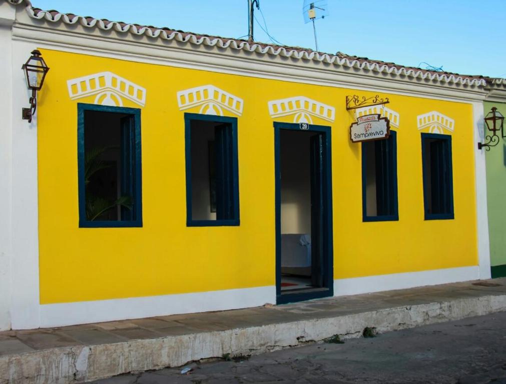 um edifício amarelo com janelas pretas numa rua em Pousada Sempreviva em Rio de Contas