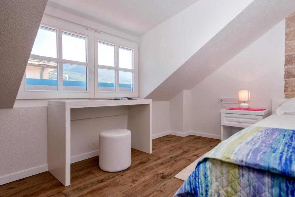 a bedroom with a desk and a bed with a window at Villa Riva in Jelsa