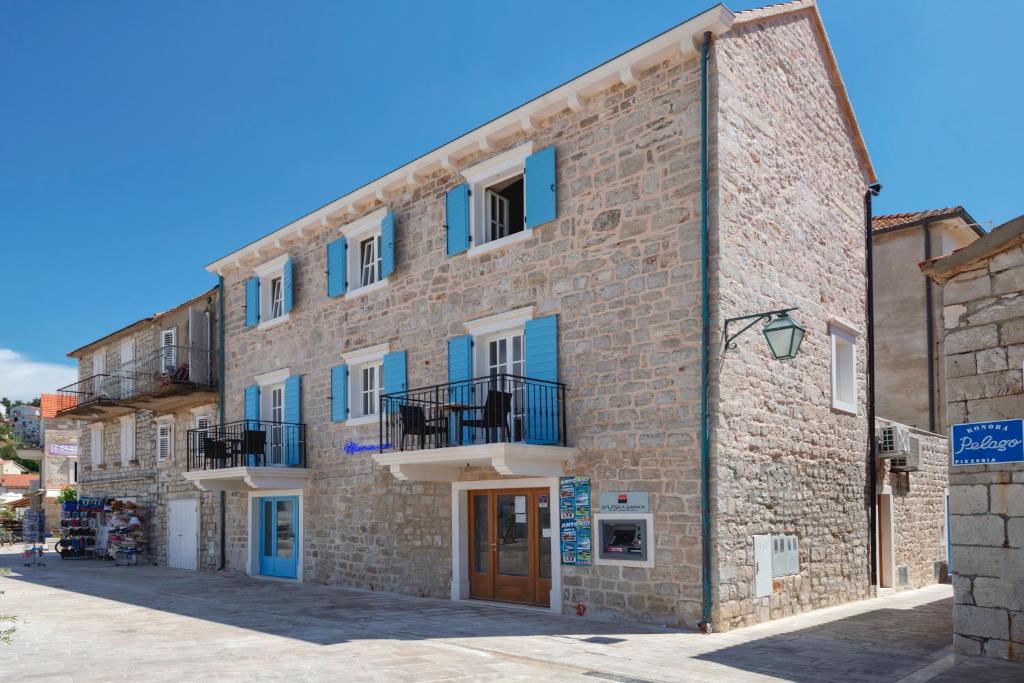 a large brick building with blue doors and windows at Villa Riva in Jelsa