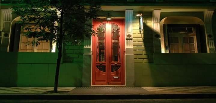 una puerta roja al lado de una casa en Casa Chango Hostel en Tandil