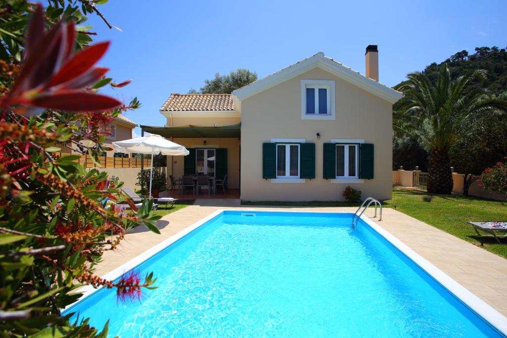 a villa with a swimming pool in front of a house at Kydonies Villas in Lefkada Town
