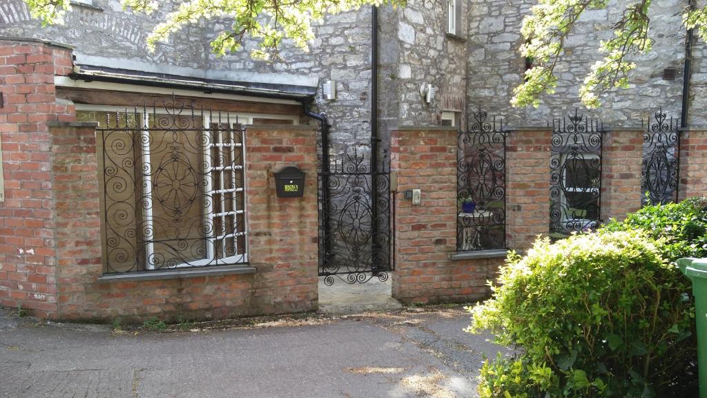 einen Eingang zu einem Backsteingebäude mit schmiedeeisernen Toren in der Unterkunft Historic Hideaway in Cork City Centre in Cork