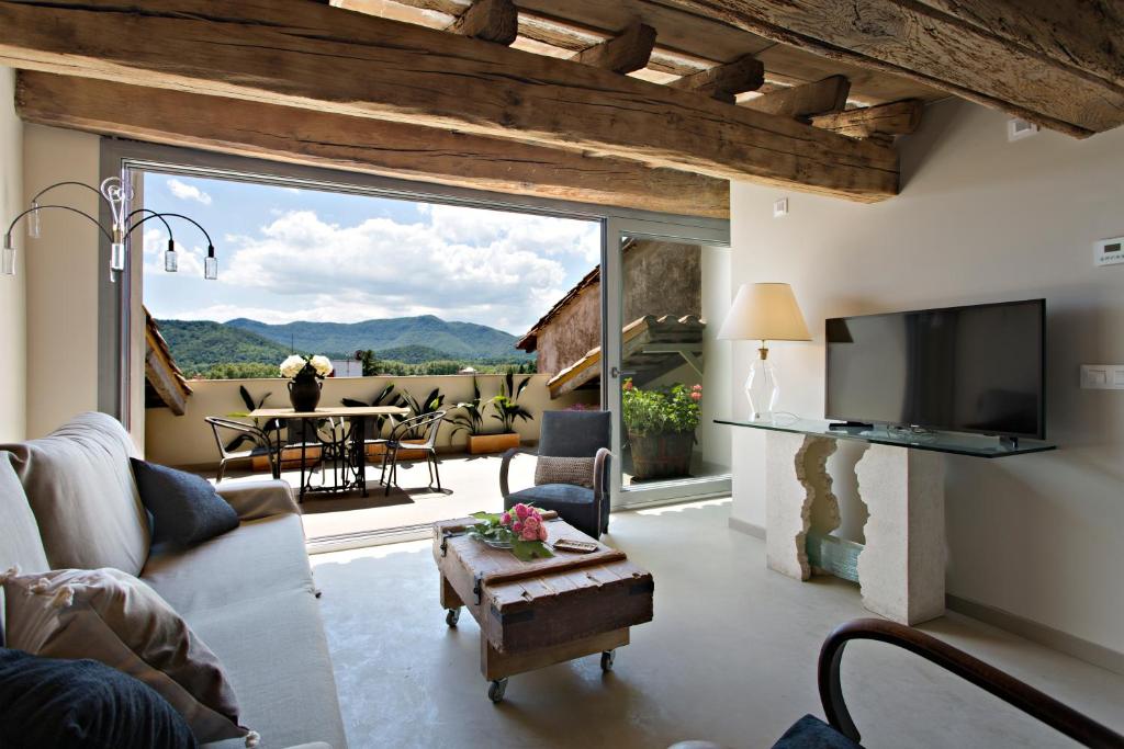 a living room with a tv and a large window at El Jardinet de Sant Esteve in Olot