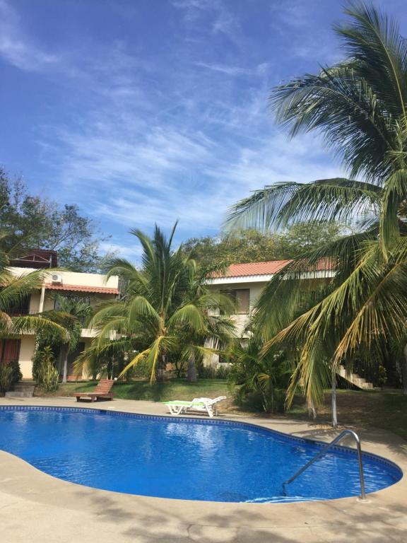 una piscina frente a un complejo con palmeras en Las Colinas de Playas del coco, en Coco