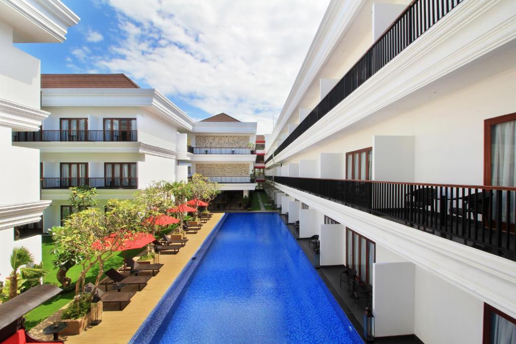 a corridor of a building with a swimming pool at Grand Palace Hotel Sanur - Bali in Sanur