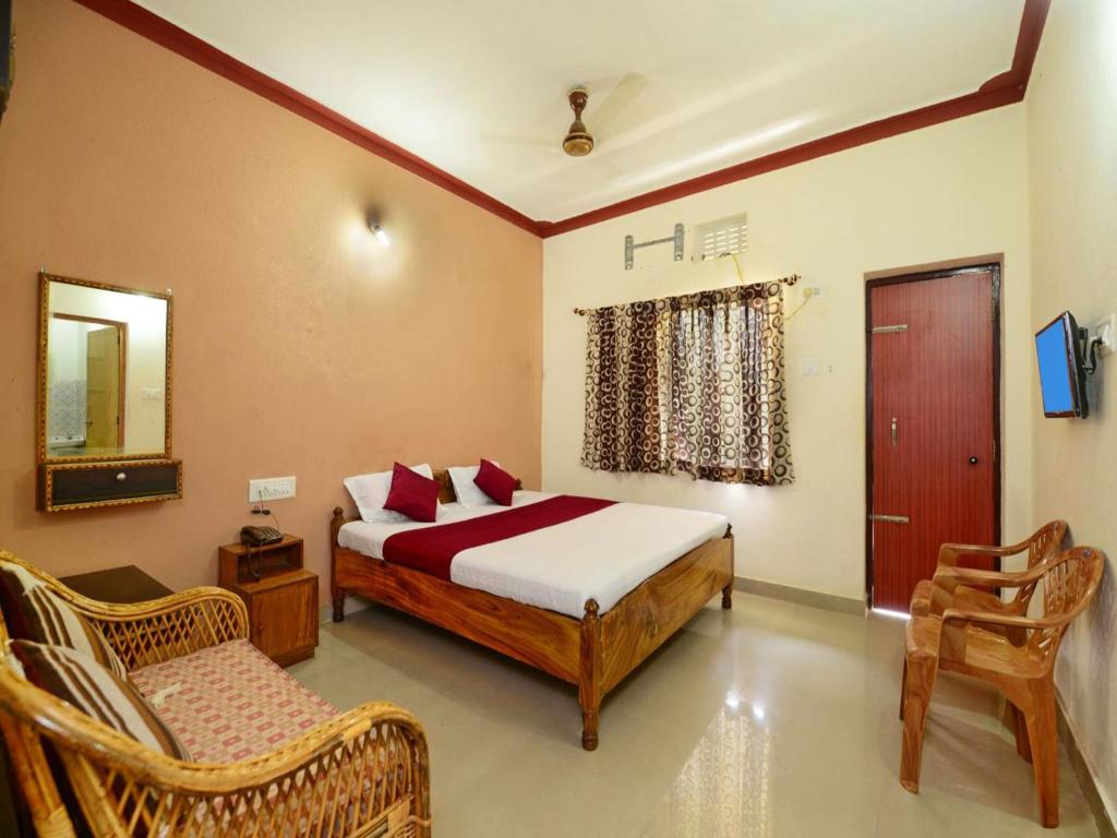 a bedroom with a bed and two chairs in it at Surya Inn in Konārka