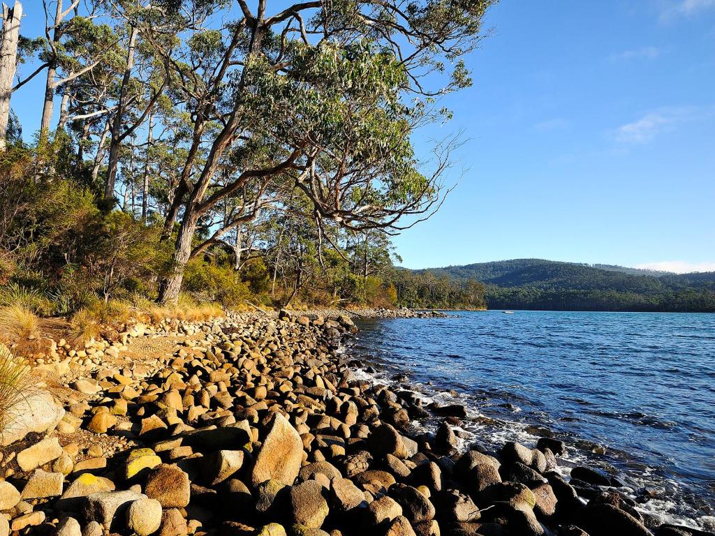um grande grupo de rochas na margem de um lago em NRMA Port Arthur Holiday Park em Port Arthur