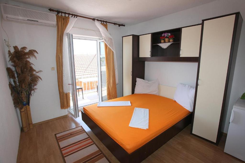 an orange bed in a room with a window at Apartments Alissa in Hvar