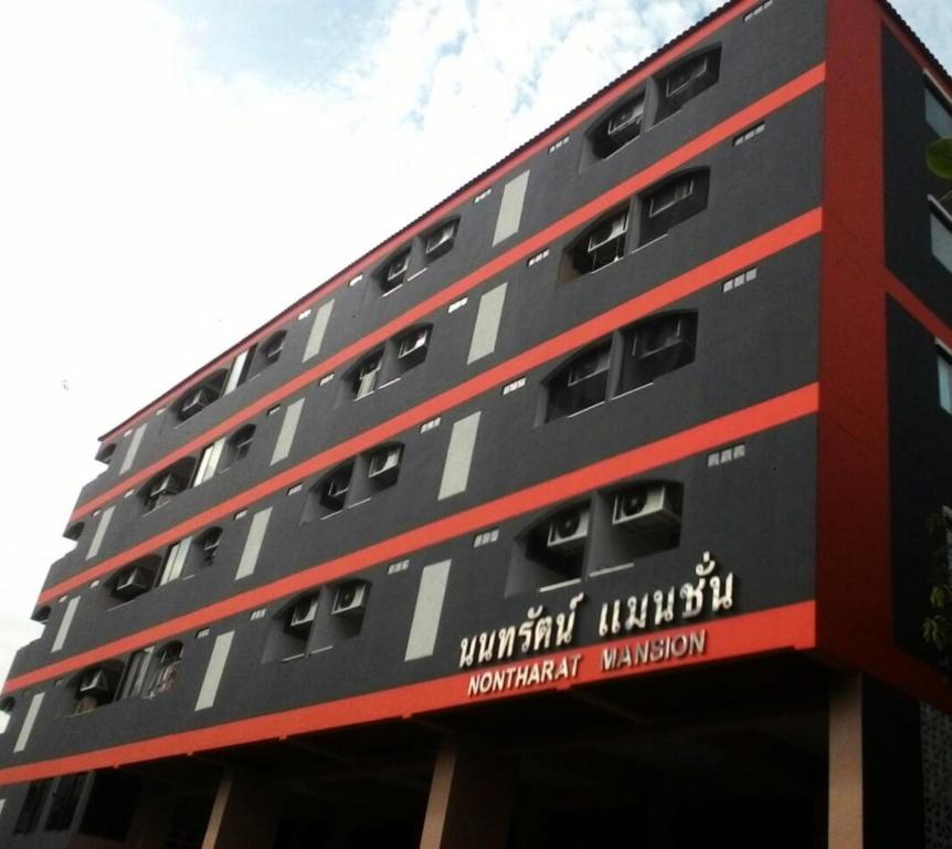 a tall building with a red and black facade at Nontharat Mansion in Nonthaburi