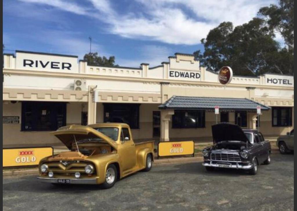 dos camiones viejos estacionados frente a un motel en Edward River Hotel, en Deniliquin