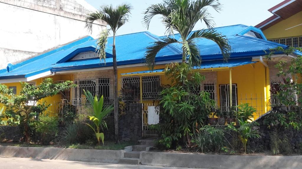 a yellow house with a blue roof and palm trees at Yellow House Vacation Rental in Subic