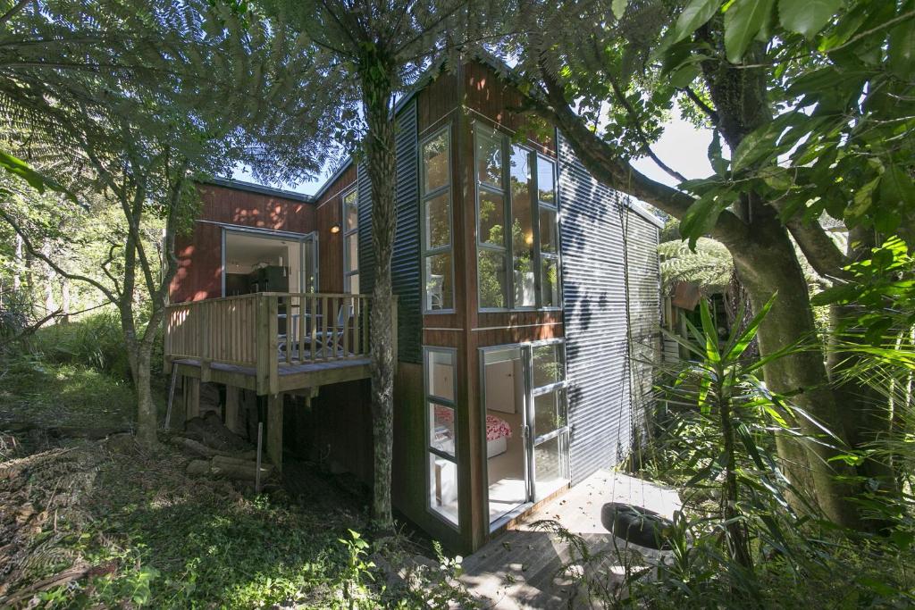 ein winziges Haus im Wald mit einem Baum in der Unterkunft Ted's Cottage near Little Oneroa Beach by Waiheke Unlimited in Oneroa