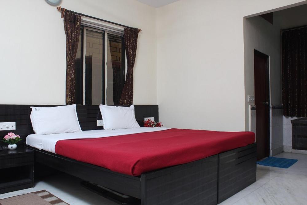 Hotel Nest International في كولْكاتا: غرفة نوم بسرير كبير مع بطانية حمراء