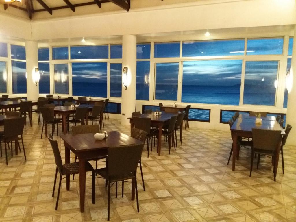 a restaurant with tables and chairs and a view of the ocean at Eagle Point Beach and Dive Resort in Mabini