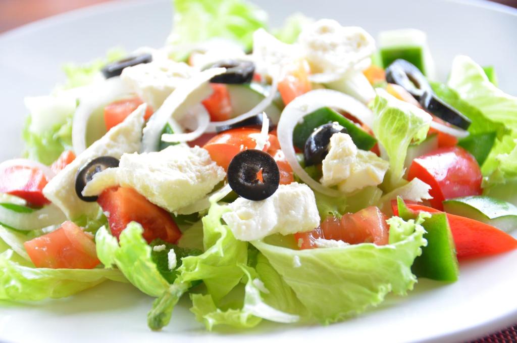 a salad with lettuce and tomatoes and olives on a plate at Cocotinos Sekotong Lombok in Sekotong