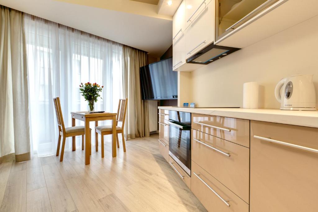 kuchnia ze stołem, 2 krzesłami i oknem w obiekcie Apartment Royal III w mieście Białystok