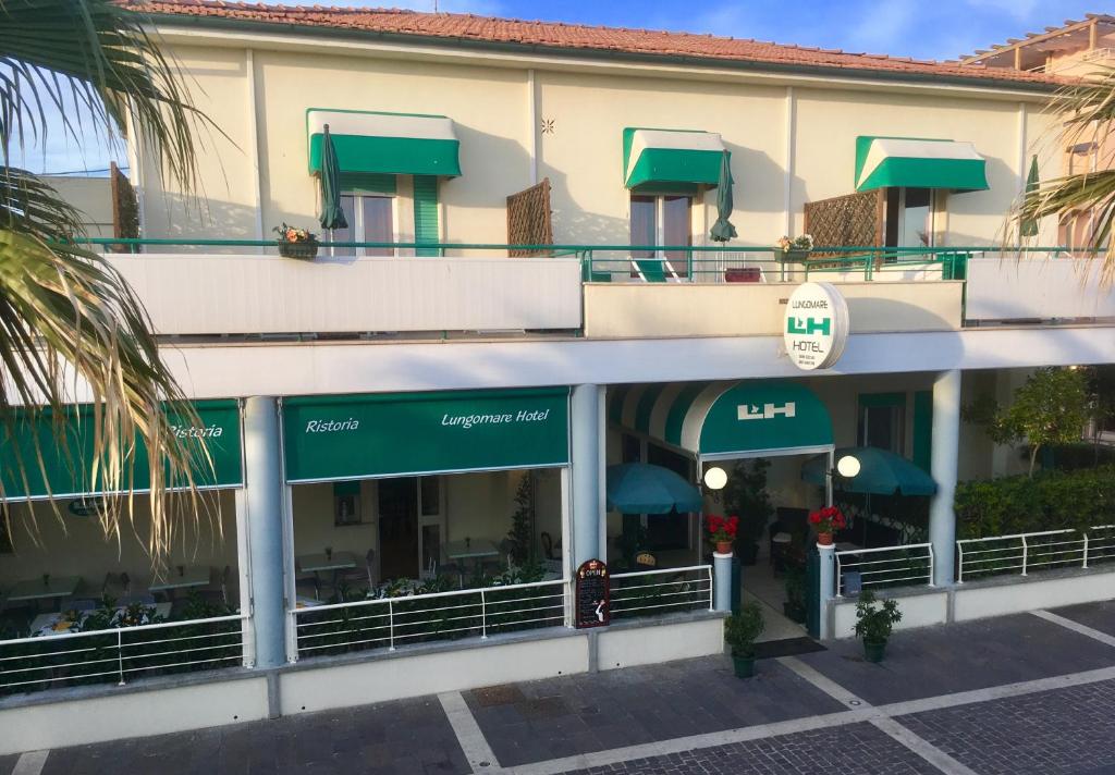 a building with green awnings and a restaurant at Lungomare Hotel in Marina di Cecina