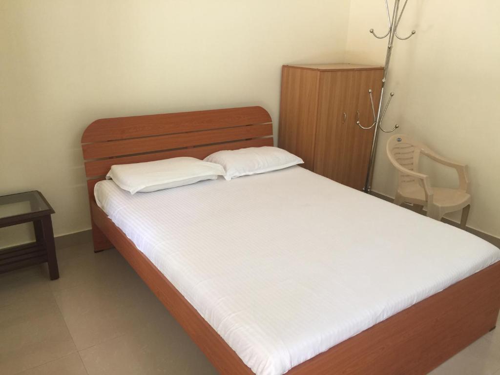 um pequeno quarto com uma cama com lençóis brancos em Palm Grove Service Villa em Cochin