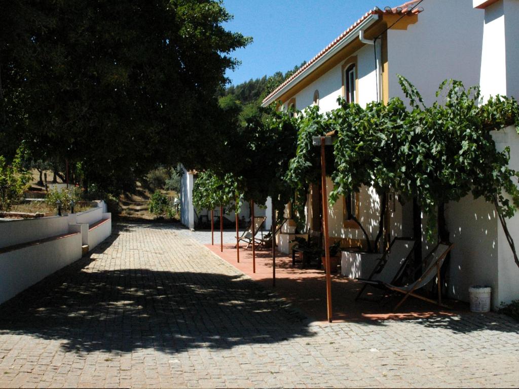 a brick walkway with chairs and trees next to a building at Quinta Do Vaqueirinho - Agro-Turismo in Marvão