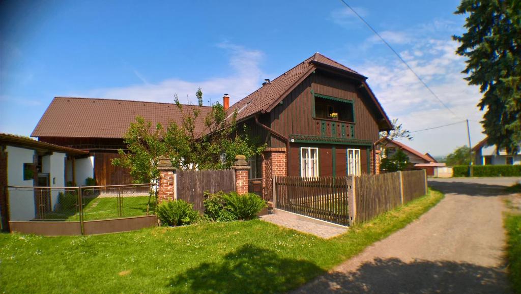 ein braunes Haus mit einem Zaun im Hof in der Unterkunft Chalupa Pod Drábskými světničkami in Mnichovo Hradiště