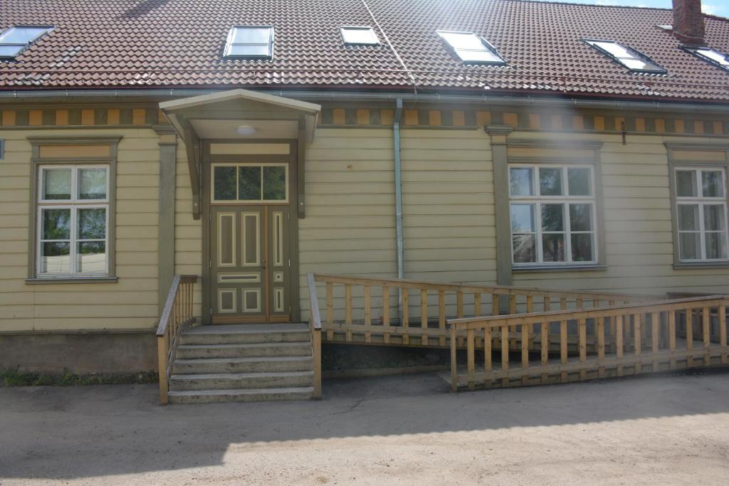 une maison jaune avec une terrasse couverte en bois et des escaliers dans l'établissement Vanalinna apartement, à Viljandi