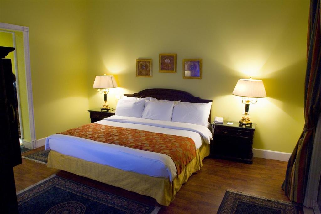 a bedroom with a large bed and two night stands with lamps at Helnan Auberge Fayoum in Fayoum Center
