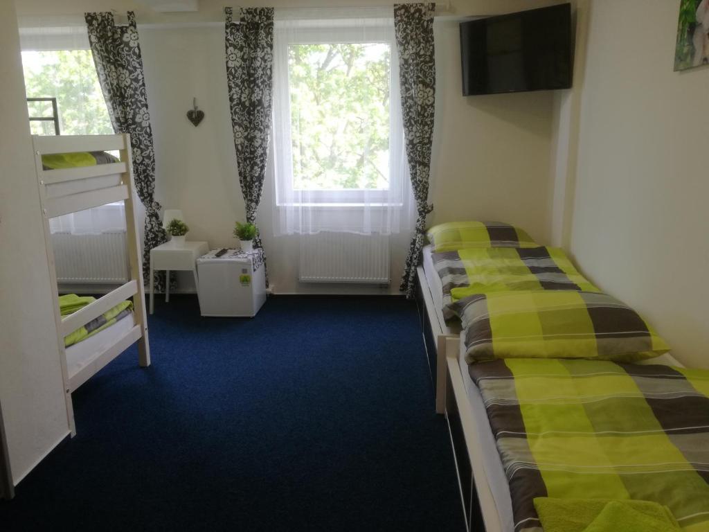dwa łóżka w pokoju z oknem w obiekcie Sporthotel Zimní stadion Benešov w mieście Benešov