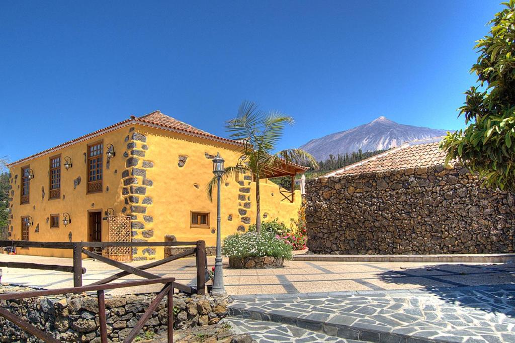 a yellow building with a mountain in the background at Casonas de Marengo in Icod de los Vinos