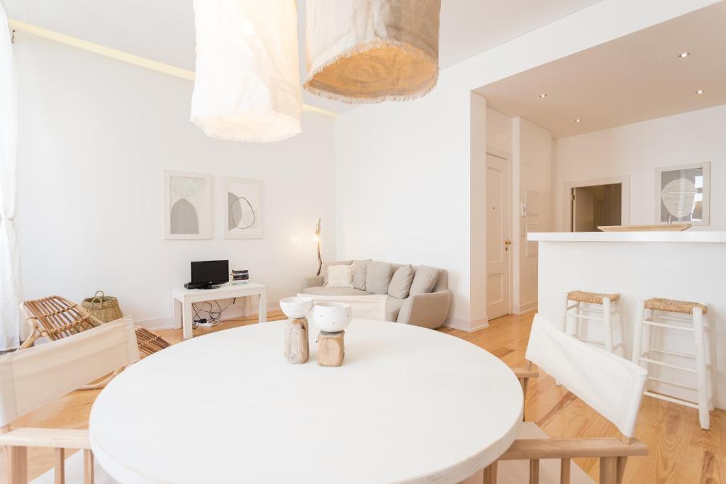 - un salon blanc avec une table et des chaises blanches dans l'établissement FLH Baixa Modern Apartment, à Lisbonne