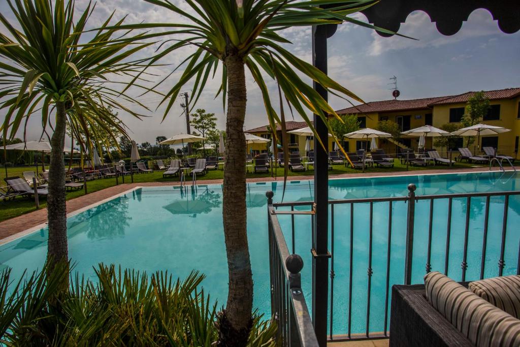 - une piscine bordée de palmiers et un complexe dans l'établissement Residence Karina, à Moniga del Garda