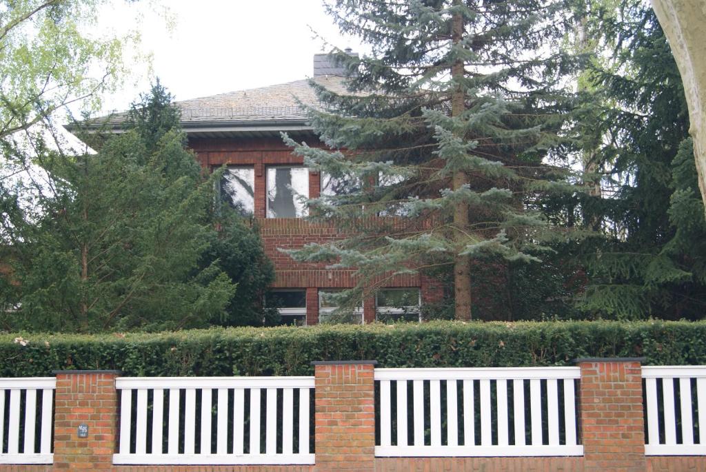 un banco blanco frente a una casa con un árbol en "Am Griebnitzsee" 14482 Potsdam-Babelsberg, en Potsdam