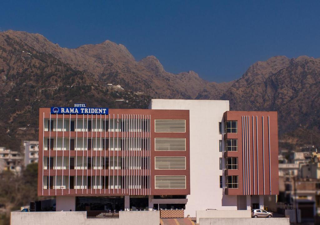 a building with a sign on it with mountains in the background at Rama Trident, Katra in Katra