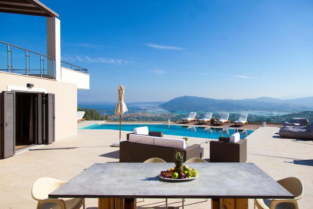 a patio with a table and chairs and a pool at Alivia Lefkas Luxury Villas in Apolpaina
