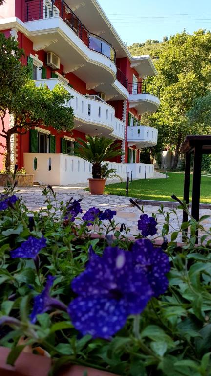 un edificio con flores púrpuras delante de él en Oasis Exclusive, en Parga