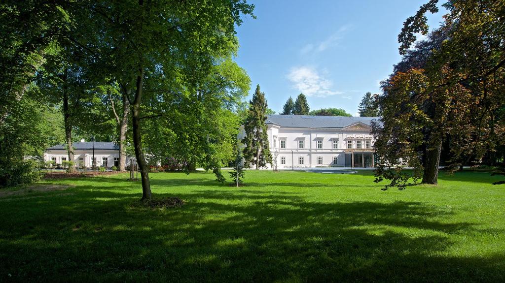 een groot wit huis met bomen ervoor bij Zámek Ratměřice - Hotel & Resort in Ratměřice
