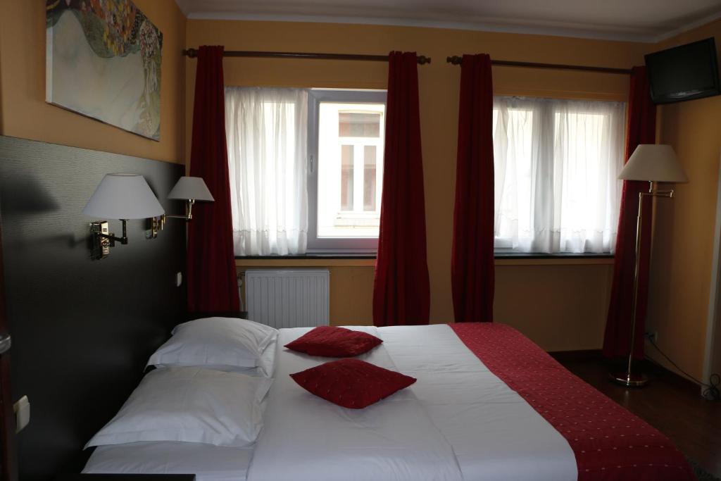 Il Siciliano - Duc de Bouillon في بوالون: غرفة نوم بها سرير ووسادتين حمرا