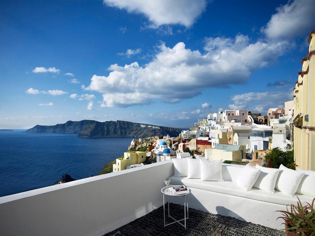 um sofá branco sentado numa varanda com vista para o oceano em 1864 The Sea Captain's House em Oia