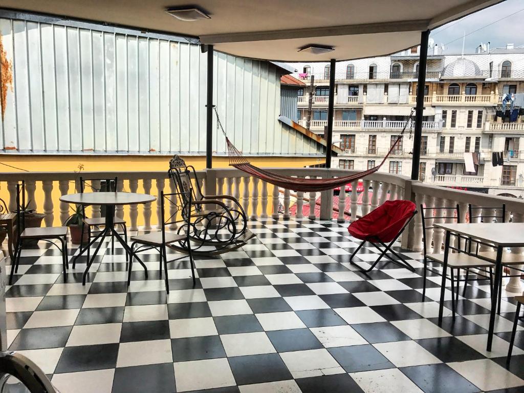 un balcón con mesas, sillas y un columpio en Gurami Guest House 1 en Batumi