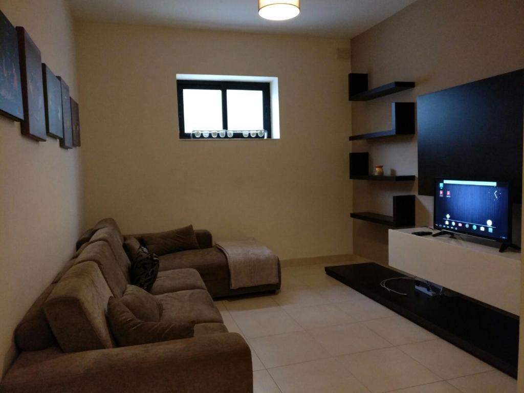 Il comprend un salon doté d'un canapé et d'une télévision à écran plat. dans l'établissement Mandalay, à Mellieħa