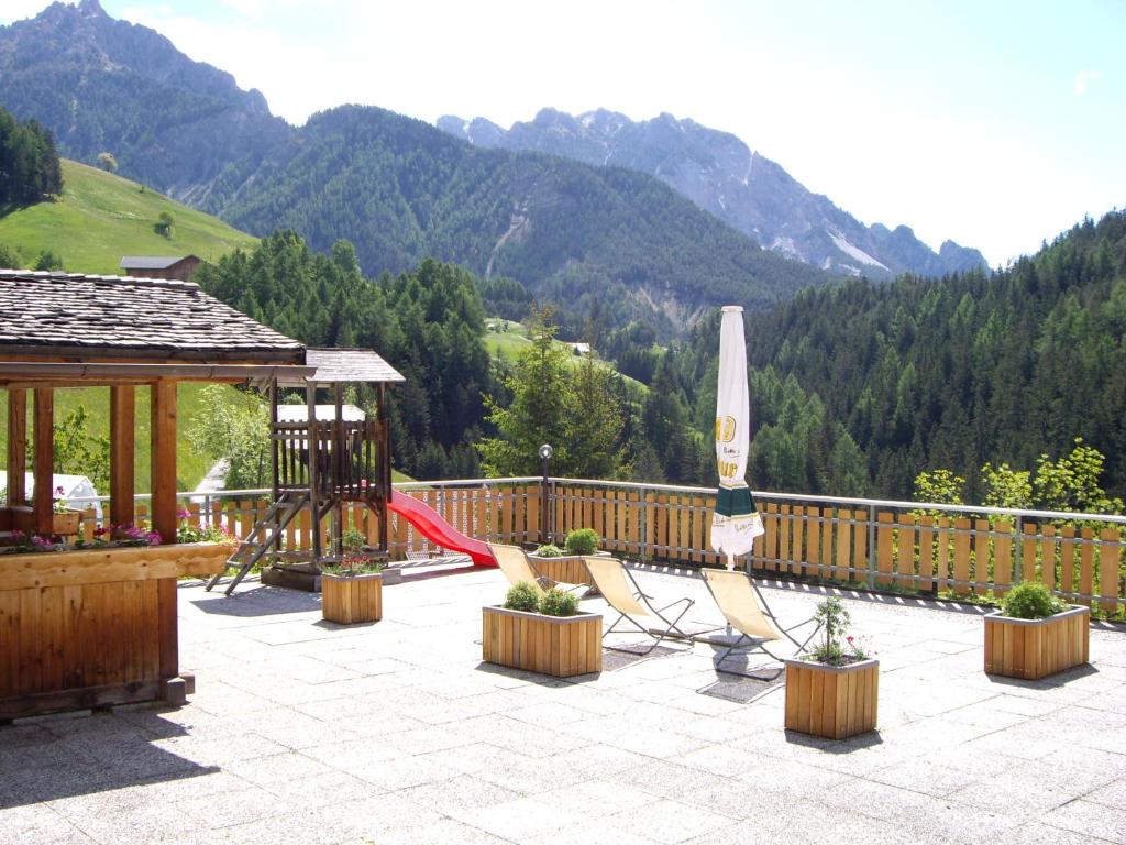 een patio met een speeltuin met een schommel en een parasol bij Soroea in San Vigilio Di Marebbe