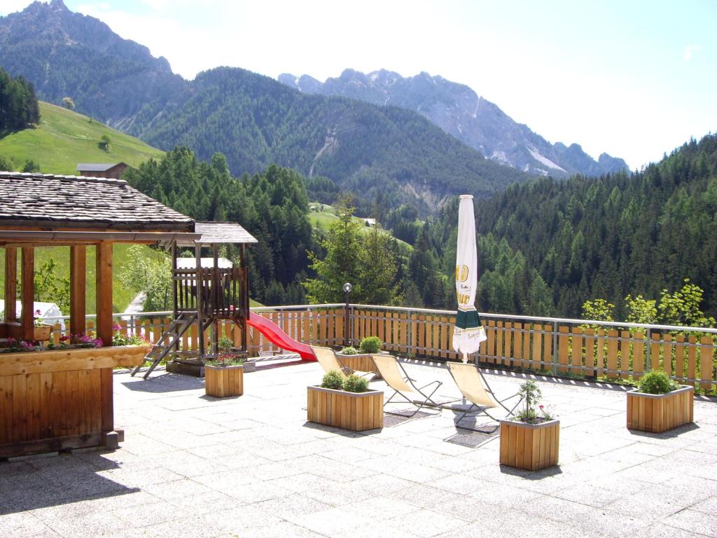 patio z placem zabaw z huśtawką i parasolem w obiekcie Soroea w mieście San Vigilio di Marebbe