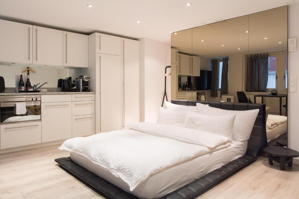 a bedroom with a white bed and a kitchen at Top city center location by Airhome in Zug