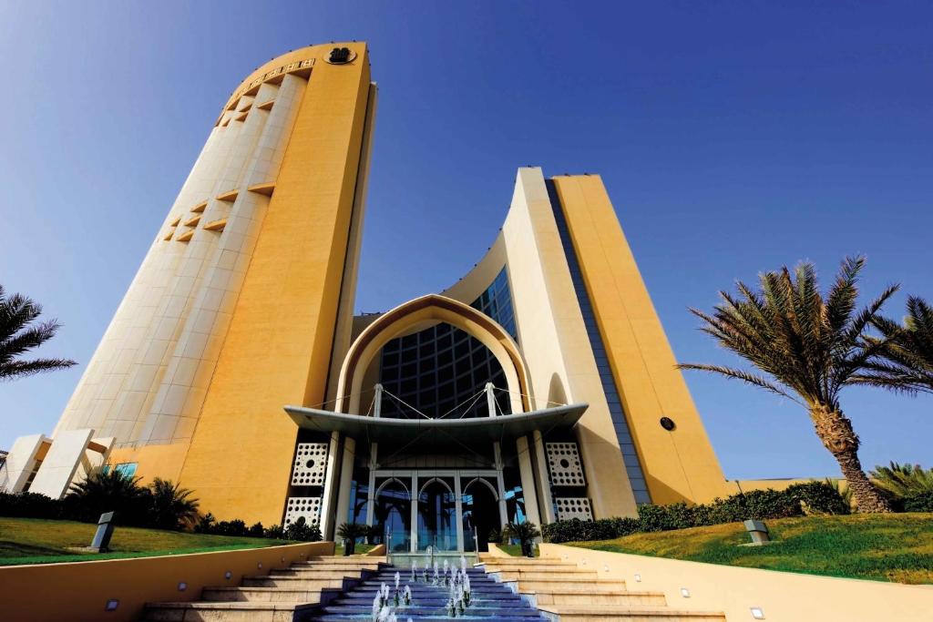 a building with a palm tree in front of it at Corinthia Tripoli in Tripoli